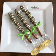 chocolate covered pretzels wrapped in cellophane and tied with green ribbons on a white plate