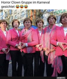 a group of women in pink jackets and black pants standing next to each other on the street