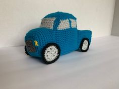 a crocheted blue toy car sitting on top of a white table next to a wall