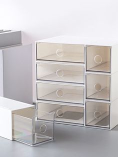 several clear drawers are stacked on top of each other in this white and grey room