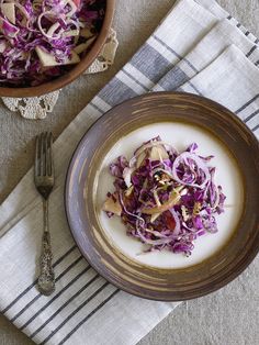 two bowls filled with food on top of a striped table cloth next to silverware