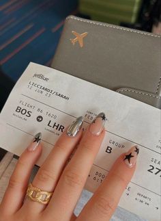 a woman's hand with some nail polish on it next to an airplane ticket