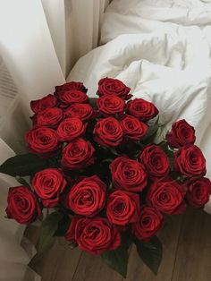 a bouquet of red roses sitting on top of a bed