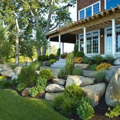 a house that has some rocks in front of it and landscaping around the outside area