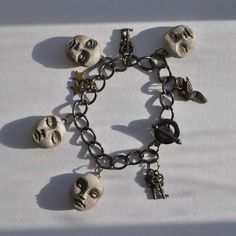 a bracelet with skulls and keys attached to it on a white tablecloth covered surface