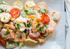 a white plate topped with pasta and shrimp salad next to broccoli florets