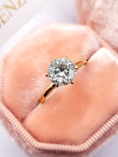 an engagement ring with a diamond in it on a pink velvet case, close up