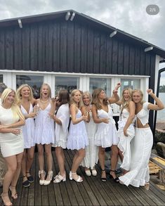 a group of women standing next to each other on a wooden deck near the ocean