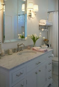 a bathroom with a sink, mirror and lights on the wall next to the toilet