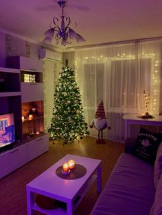 a living room filled with furniture and a christmas tree in front of a tv set