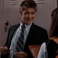 a man in a suit and tie standing next to a woman holding a binder