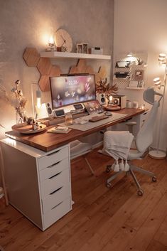 a desk with a computer on top of it in front of a wall mounted monitor