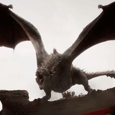 a large dragon is standing on top of a building with it's wings spread out