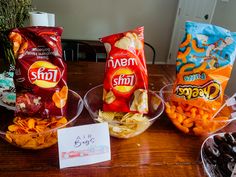 three bowls filled with snacks sitting on top of a wooden table next to a sign