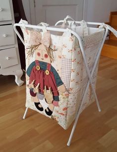 a baby crib with a teddy bear on it's back and clothes hanging from the handles