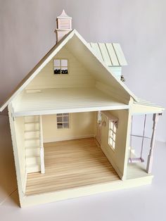 a doll house with wooden floors and white sidings on the front door, windows, and porch