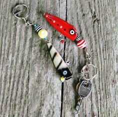 three different types of keychains on a wooden surface, one is red and the other is black