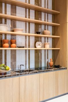 a kitchen with wooden shelves filled with dishes and vases on top of the counter