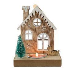 a wooden house with a lit candle in front of it and a small christmas tree