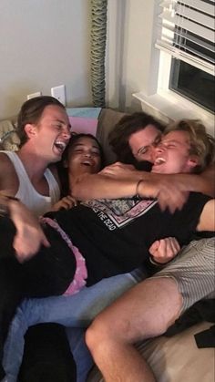 a group of people laying on top of each other in a bed with their arms around one another