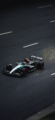 a man driving a racing car down a race track with water splashing from the front