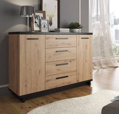 a wooden cabinet with drawers in a living room next to a white rug and window