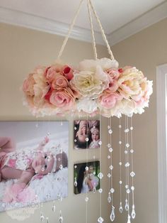 a chandelier with flowers hanging from it's sides and pictures on the wall