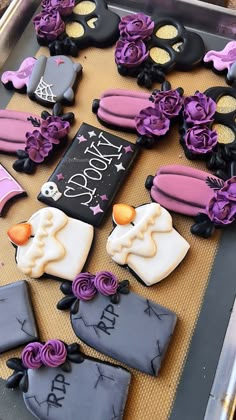 decorated cookies are arranged on a tray with purple and black icing for halloween decorations