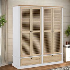 a white and wood cabinet with shutters on the doors is in front of a window