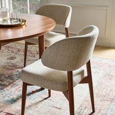 a dining room table with two chairs and a rug on the floor next to it