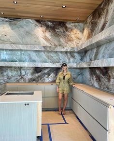 a woman standing in the middle of a room with marble walls and flooring on both sides