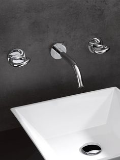 a white sink sitting under a faucet next to a wall mounted faucet