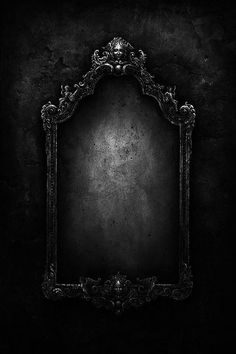 an ornate frame on a black wall with light coming from the top and below it