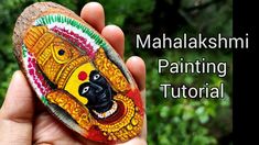 a hand holding a painted rock with the words mahaakshmami painting on it