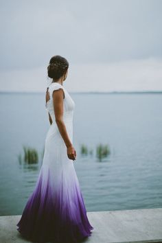 a woman in a white and purple dress looking out at the water