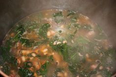 a pot full of soup with spinach and beans