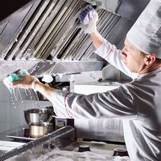 a chef is sprinkling something on the kitchen counter while wearing gloves and an apron