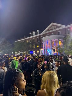 a large group of people standing in front of a building with lights on at night