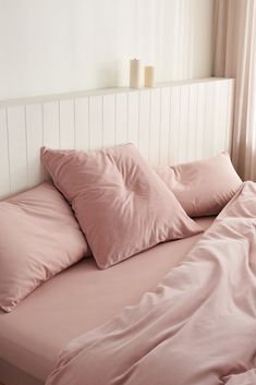 a bed with pink sheets and pillows on it