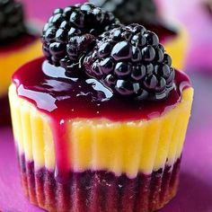 some cupcakes with berries on top of them sitting on a purple tablecloth