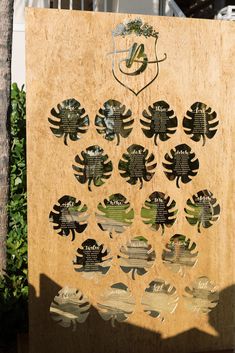 a wooden sign with many different types of leaves and birds on it's side