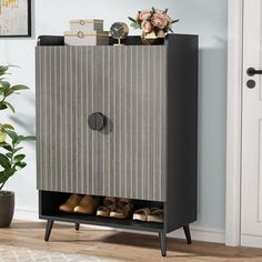 a small cabinet with shoes on it in front of a door and potted plant