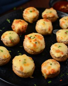 mini pizzas with cheese and parsley on a black plate, ready to be eaten