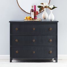 a black dresser with flowers and bottles on top