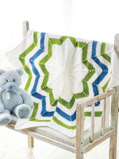 a teddy bear is sitting on a chair next to a crocheted blanket that looks like a star