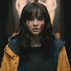 a woman with blood on her face standing in front of a building