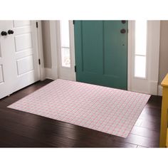 a pink and white rug sitting on top of a wooden floor next to a green door