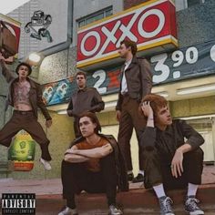 a group of young men standing on top of a street next to a store front