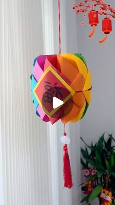 an origami lantern hanging from a string with chinese characters on it and red tassels