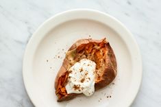 a white plate topped with a baked potato covered in cream